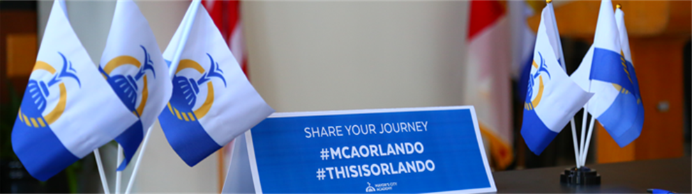 Table with Orlando flag and banners displaying #MCAOrlando and #ThisIsOrlando hashtags.